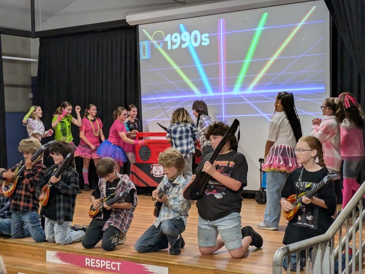 Group of children in rock and roll outfits on stage performing